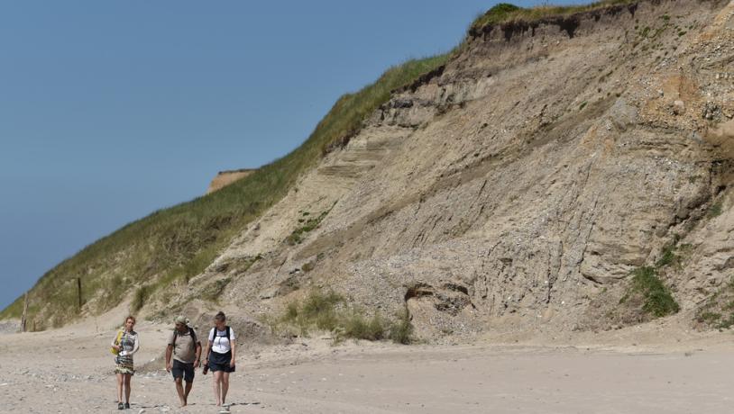 Tre mennesker går på stranden ved Bovbjerg Klint